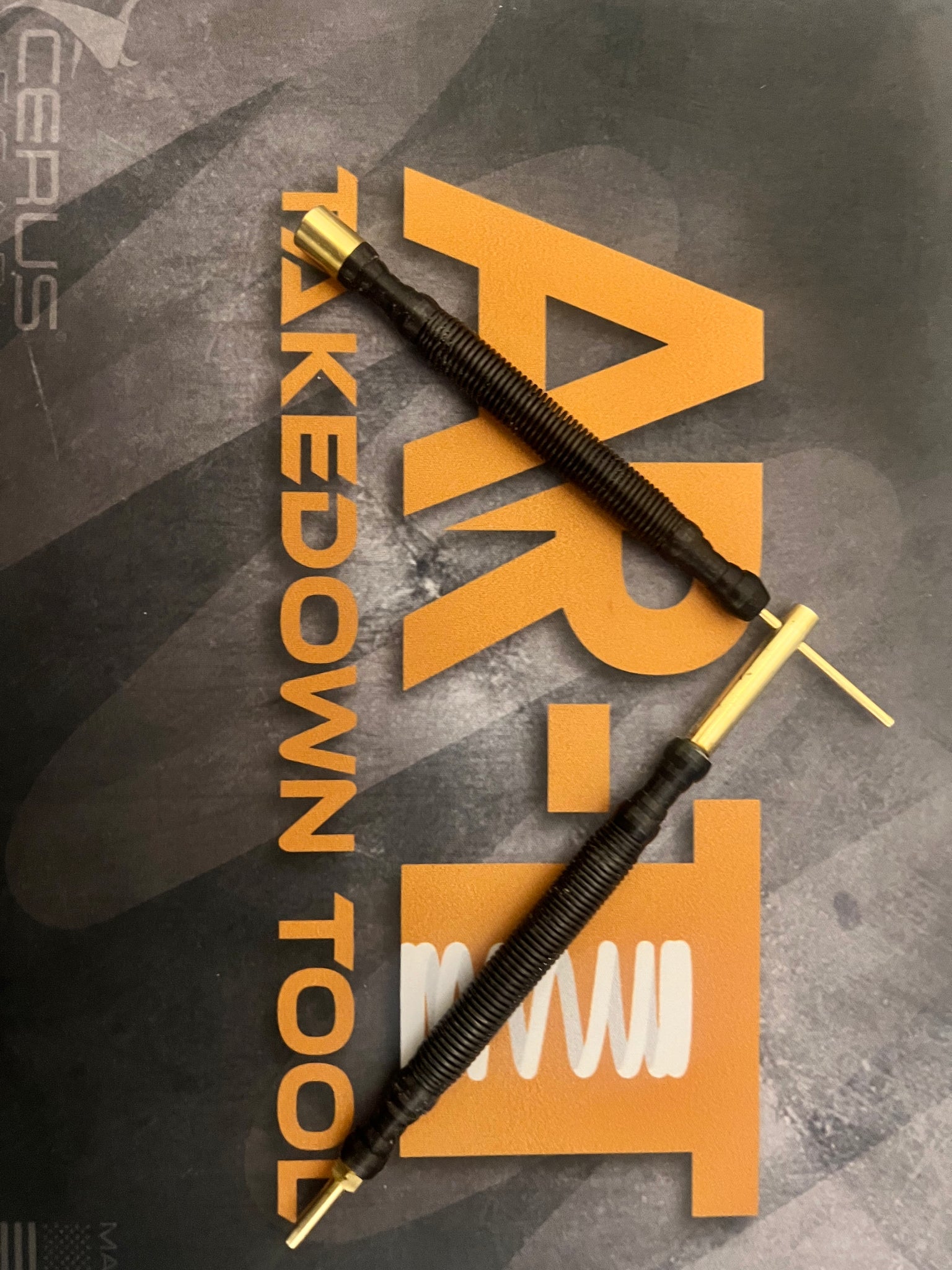 Two-piece brass gunsmithing tool set displayed on an AR-TT gun cleaning mat.